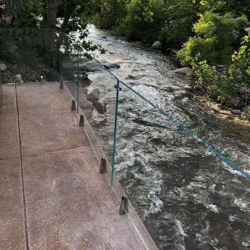 balcony with frameless glass railings looking over running water
